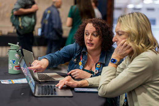 Audra and an educator side by side in the Educators Lounge, as Audra points to a computer screen engaged in conversation.